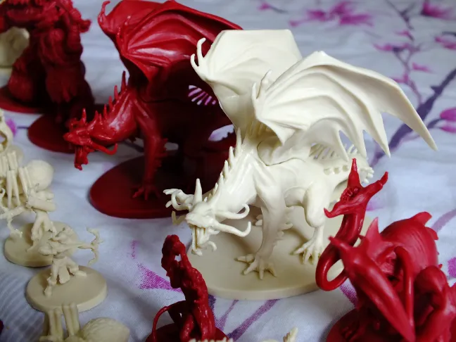 White and red dragon miniatures with spread wings towering over smaller figures